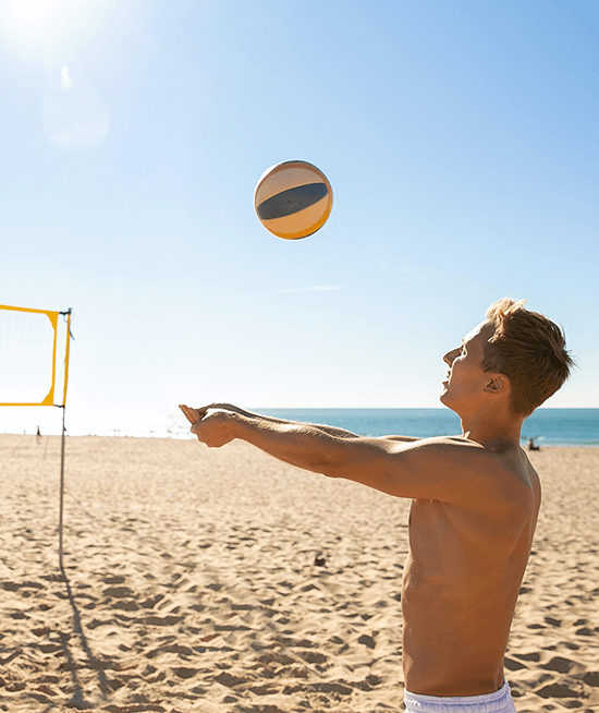 Man practicing volleyball alone on beach