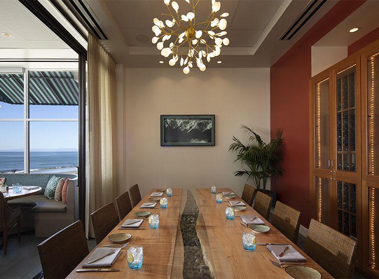 A long wooden table set for dining in a room with a view.