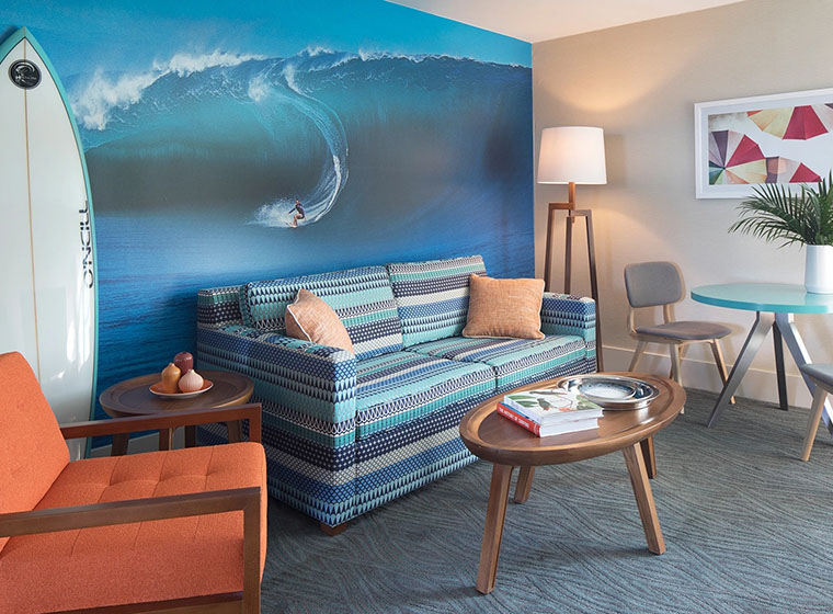A lounge area with a sofa, coffee table, chair, and wall art